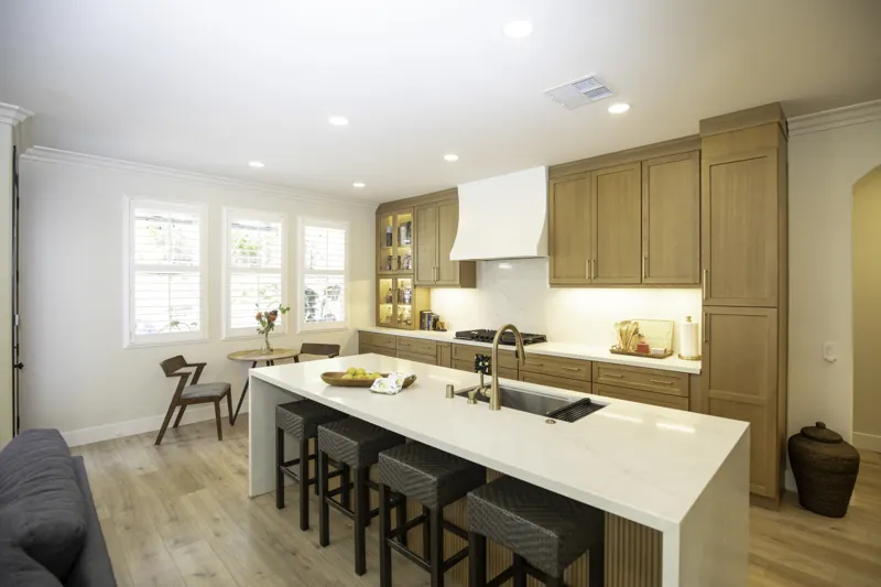 Picket Fence kitchen with wood cabinets, white island and woven stools