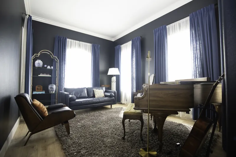 Dark blue sitting room with a piano and tall windows